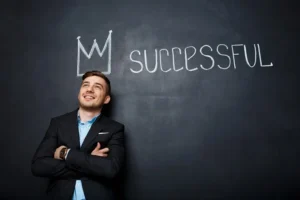 Confident businessman standing in front of a chalkboard with the word "Successful" written on it.